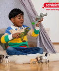 Child playing with dinosaur toys and horse figurines on a rug near a teepee