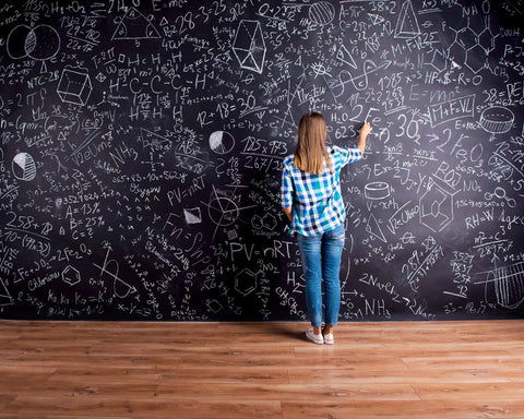 Person writing on a large chalkboard wall with equations using Chalkboard Paint Kit Two Pack Black Brush On Dope Finish Delivers Smooth Writable And Erasable Slate Like Surface For Interior Use On Non Porous Surfaces Like Chalkboards Tables Walls And Creative Decor