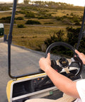 Heavy Duty Golf Cart Steering Wheel With Slick Non Slip Grip Fits Club Car EZGO And Yamaha Models For Smooth Handlein And Reliable Daily Cruisin in use while driving on a path.