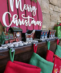 Top Shelf Cast Iron 3D Train Christmas Stocking Holder With Santa Sleigh And Four Rail Carts Six Stocking Hooks above red and green stockings.