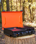 2364 12 By 14 Camping Griddle With Side Burner Nonstick Ceramic Titanium Coated Surface open on tree stump in forest