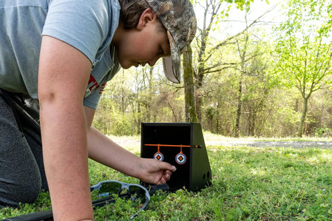 Person adjusting Air Strike Pellet Trap For 800fps Airguns With Interchangeable Silhouette Targets And Paper Target Compatibility Heavy Duty Steel Backdrop Catcher Black outdoors