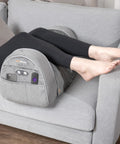 Carepeutic Contoured Leg Rest Wedge With Vibration Massage And Heat on gray sofa, supporting user’s legs with remote controls and soft touch surface.