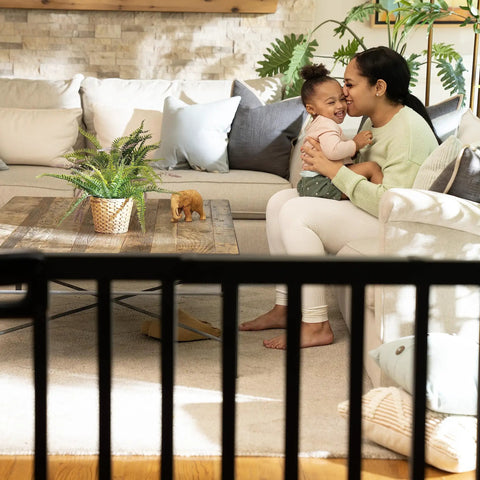 Family sitting in living room behind Deluxe Stair Gate For Pets And Kids, Super Easy Install No Fuss Secure Build, Black Wood