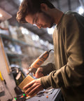 WEN 23190 rotary tool in orange/black used on a wooden block in a workshop, with a person wearing safety glasses.