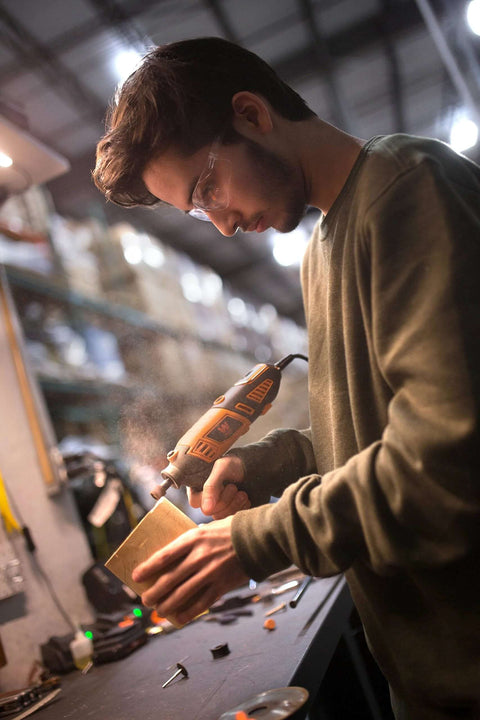 WEN 23190 rotary tool in orange/black used on a wooden block in a workshop, with a person wearing safety glasses.