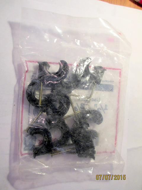 Bag of black circular clips with nails for securing cables, packaging labeled with date 07/07/2015.
