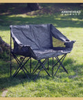 Portable Folding Double Duo Camping Chair Loveseat For Two set up on grass, showing padded seat and drink holders.