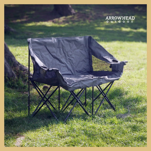 Portable Folding Double Duo Camping Chair Loveseat For Two set up on grass, showing padded seat and drink holders.