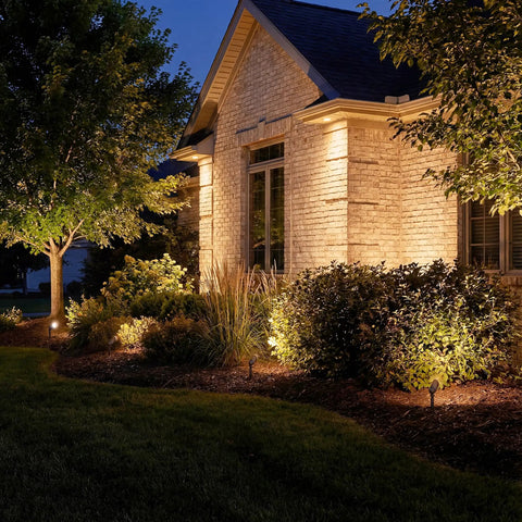12V MR16 Adjustable Cowl Brass Accent Light for landscape lighting in Centennial Brass finish illuminating outdoor house garden scene
