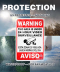 The Real Deal 24 Hour Security Camera Alert Eight By Twelve Inch Reflective Aluminum Yard Sign with bilingual warning about surveillance.
