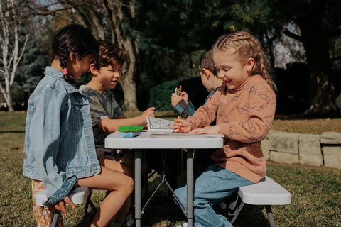 Children playing at a Compact Kids Picnic Table With Foldable Benches Under The Table And Built In Carry Handle For Easy Transport