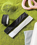 Black and white jersey sleeve bands with hook and loop fasteners for shirts, shown on a green surface with sports accessories.