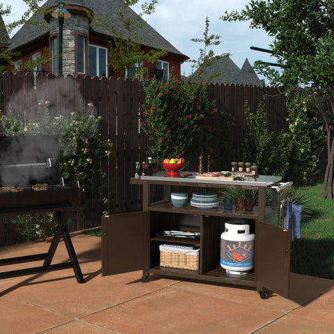 Outdoor Wood Grill Prep Table With Stainless Steel Top Waterproof Cover Dark Brown Finish Solid Wood Construction No Plastic Open Shelf For Quick Access Storage Heavy Duty Outdoor Kitchen Station in a backyard setting next to a grill.