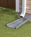 Heavy Duty Two Pack Premium Rubber Downspout Splash Blocks Built Damn Tough With A Slick Stone Texture For Top Shelf Yard Drainage And Clean Rainwater Management In Gray positioned under gutter outlet on grass.