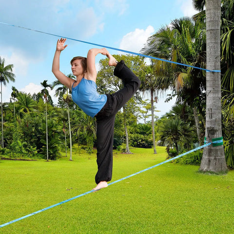 Person balancing on Beginner Slackline Kit With 50 Foot Main Line And Training Line, Tree Protector, Ratchet Covers in a backyard