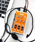 Portable Three Channel DJ Mixer For On The Go USB Or Battery Powered Pocket Audio Mixer With 3.5mm Inputs And Built In On Off Switch In Bright Orange For Quick Street Setup connected to a laptop and headphones.