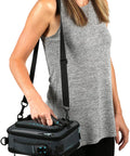 Heavy Duty Expandable Lunch Pack With Dual Food Containers And Pro Grade Ice Walls For Hella Superior Cooling And Zero Leak Stress In Smooth Black And Blue Travel Bag, carried by a woman.