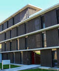 Modern building with wood paneling, large windows, and concrete base, showcasing contemporary architecture.