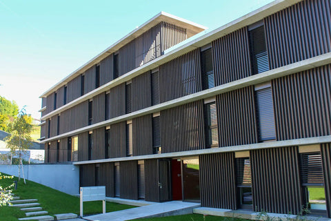 Modern building with wood paneling, large windows, and concrete base, showcasing contemporary architecture.