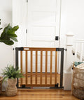 Oak Wood And Metal Baby And Pet Gate For 36 To 60 Inch Openings, 30 Inch Tall, no drill, pressure mount in doorway with plants nearby.