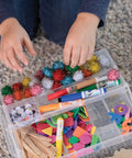 Child's hands reaching for DIY craft supplies with Premium Natural Wood Craft Sticks For DIY Arts And Crafts in a kit