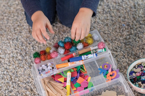 Child's hands reaching for DIY craft supplies with Premium Natural Wood Craft Sticks For DIY Arts And Crafts in a kit