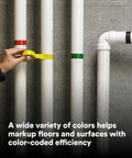 Hand applying Vinyl Tape 764 General Purpose White 3 Inch By 36 Yard Roll for color coding on pipes against concrete wall