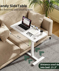 Mobile Standing Desk With Pneumatic Height Adjustment next to couch, with laptop and glasses on white tabletop, depth 21.3 in.