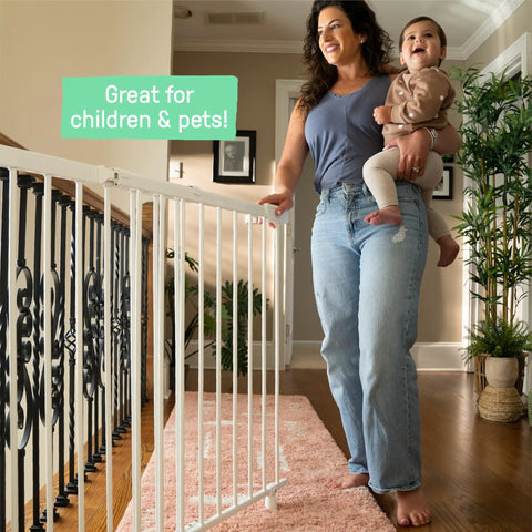 Woman holding baby next to Stairway 46W Series Baby Gate for Stairs and Dog Gate Indoor With Door, white metal safety gate in hallway.