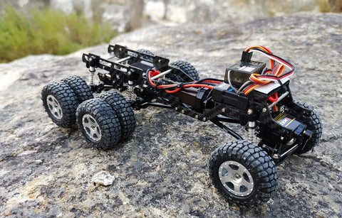Dope LCG Carbon Fiber Chassis Frame For Axial SCX24 6x6 RC Crawler Upgrade on rocky terrain showcasing wheels and structure
