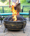 Outdoor 34 Inch Wood Burning Fire Pit Bowl with Spark Screen, Log Poker, and Grate used on patio.