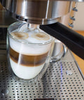 Top Tier Stainless Steel Espresso Machine With Reliable 19 Bar Italian Pump And Quick Ground Or ESE Pod Brewing Featuring Precise Temp Control And Zero Frustration Pre Brew For Killer Daily Coffee Routines making a layered espresso drink in a glass mug.