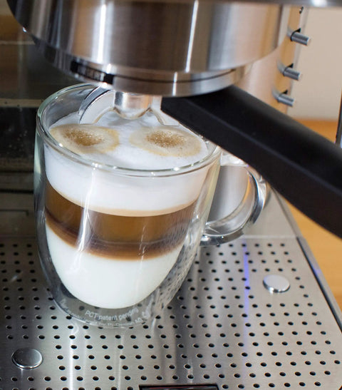 Top Tier Stainless Steel Espresso Machine With Reliable 19 Bar Italian Pump And Quick Ground Or ESE Pod Brewing Featuring Precise Temp Control And Zero Frustration Pre Brew For Killer Daily Coffee Routines making a layered espresso drink in a glass mug.