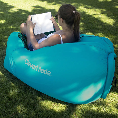 Person sitting on Inflatable Lounger Air Chair Lightweight Self Inflating Beach Chair with book in teal color outdoors