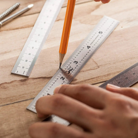 Close-up of Pro Grade Machinist Ruler Set, 6 Inch Stainless Steel with precise markings being used for drafting on wood surface.