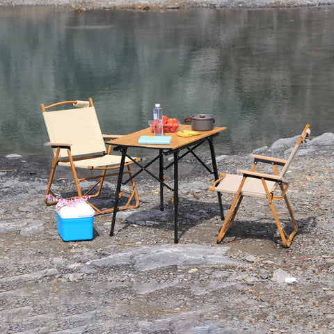 Heavy Duty Folding Table Risers 8 Pack Adjustable Leg Extenders For Straight And Bent Legs set up outdoors by a lake with chairs and food.
