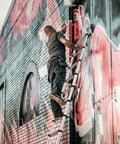 Man using a 12.5 Foot Telescoping Aluminum Ladder for Home DIY and Outdoor Use, painting graffiti on brick wall