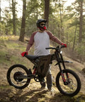 Person outdoors with X2Pro Electric Dirt Bike For Adults With 6000W Peak Motor, 60V/30Ah Battery on forest trail.