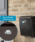 Locking Wall-Mounted Mailbox in Rubbed Bronze with decorative embossed design and secure cam lock, mounted on brick wall.