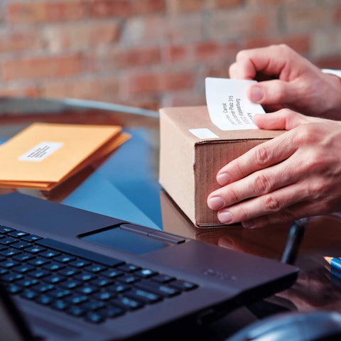 Person applying a shipping label to a box using the Straight Up Twin Turbo Direct Thermal Label Printer.