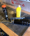 Heavy Duty Lever Grease Gun That Feels Like A Beast, 10,000 PSI Power, in a workshop setting with lubricants nearby.