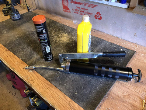Heavy Duty Lever Grease Gun That Feels Like A Beast, 10,000 PSI Power, in a workshop setting with lubricants nearby.