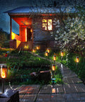 12 Pack Solar Torch Lights With Flickering Flames For Outdoor Use illuminating a garden pathway beside a house at night
