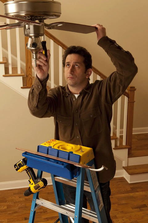 Man using Blue Ladder Accessory Kit With Open Storage Channel And Utility Hooks on stepladder, fixing ceiling fan