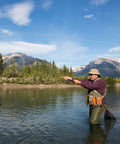 Person fishing with Backpacking Ready 3 Piece Fly Fishing Rod And Reel Starter Kit in river, mountains in background