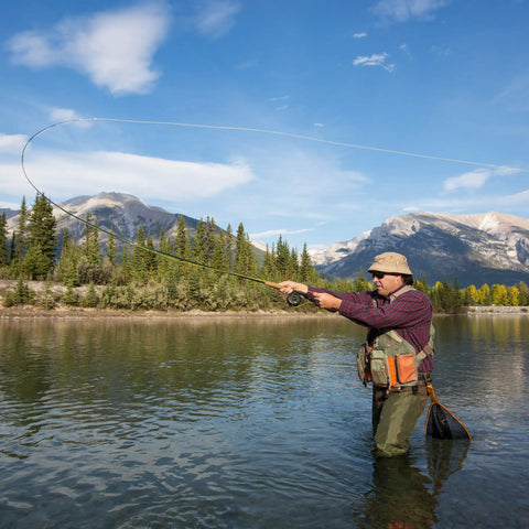 Person fishing with Backpacking Ready 3 Piece Fly Fishing Rod And Reel Starter Kit in river, mountains in background