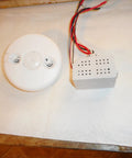 DT-300 Ceiling Occupancy Sensor With 360 Degree Coverage And Low Profile Design shown with wiring component on table.