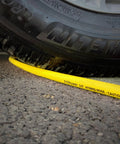 Heavy Duty Hybrid Air Compressor Hose 3/8 Inch X 50 Foot Lightweight Kink Free Airline under a tire on asphalt.