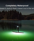 Person paddleboarding at night with Luci Original Solar Inflatable Camping Lantern With USB C Recharge illuminating the water.